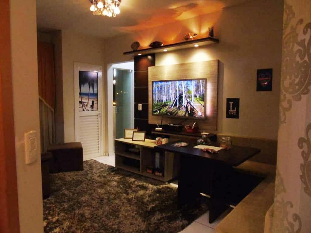 uma sala de estar com televisão na parede em Apartamento aconchegante e completo no centro de Ponta Grossa - Paraná em Ponta Grossa