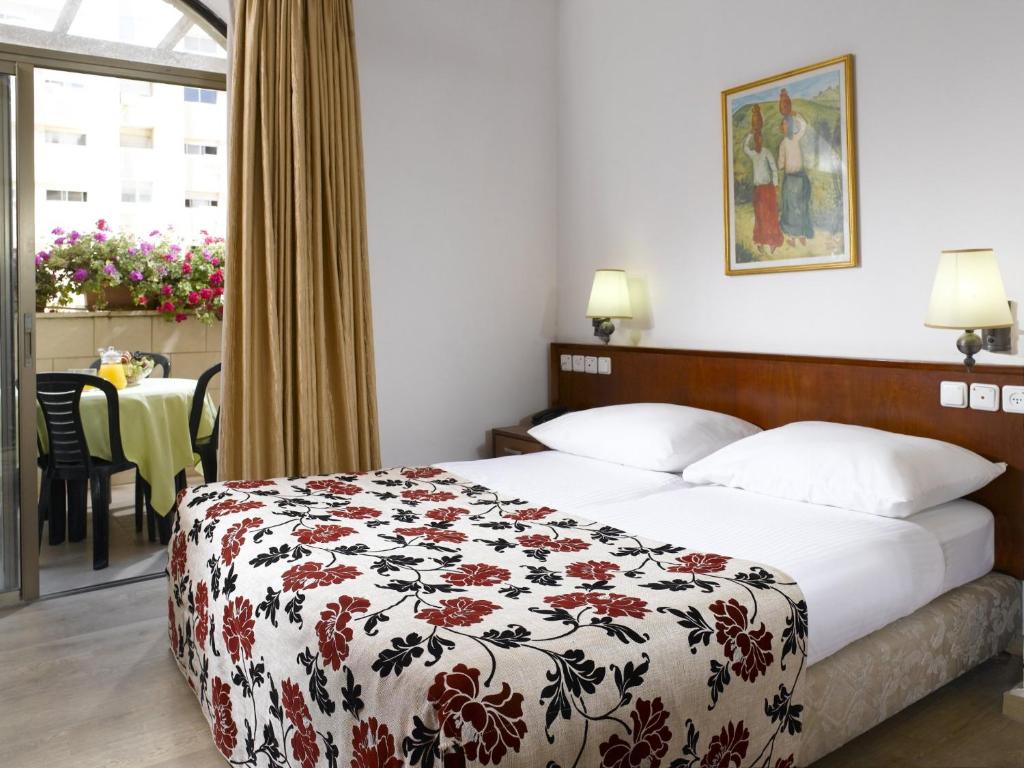 a hotel room with a bed with a floral bedspread at Lev yerushalayim - suites hotel in Jerusalem