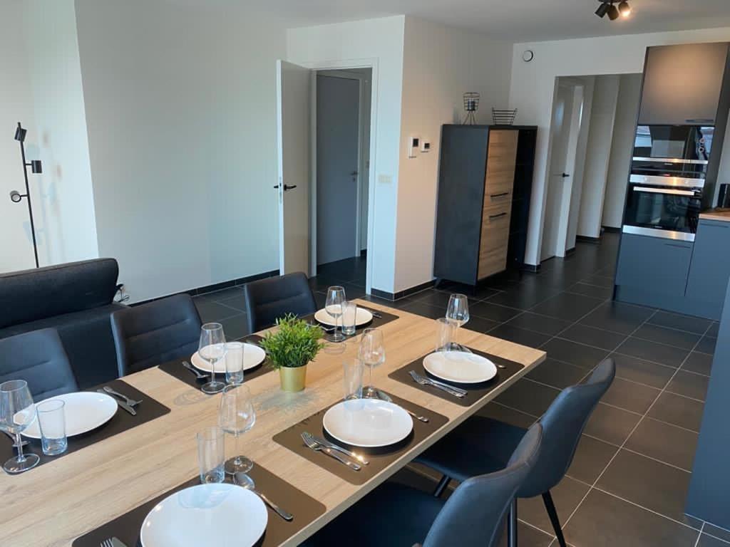 a dining room table with plates and wine glasses at Appartement Anne-Rose in Beernem