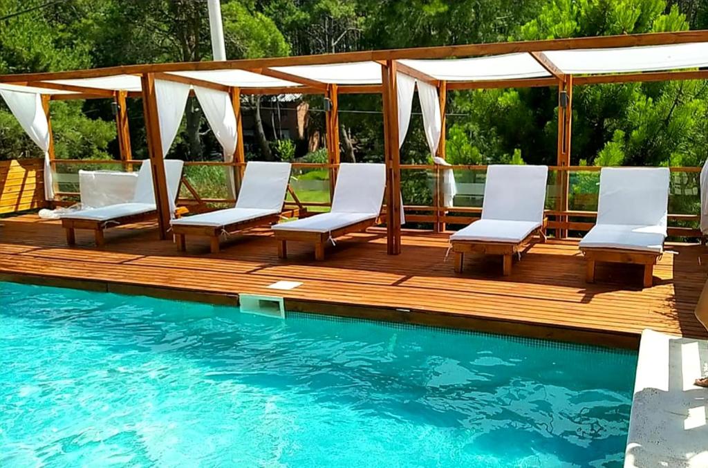 una terraza de madera con sillas y una piscina en Arena de Mar depto A, en Mar Azul