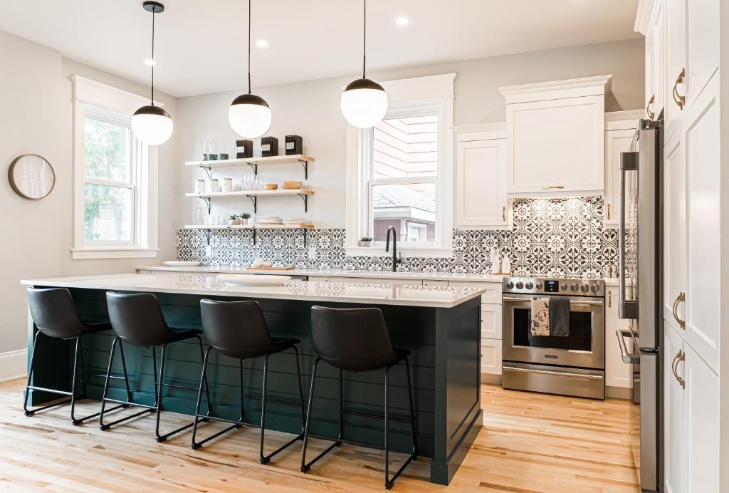 a kitchen with a large island with black bar stools at Manoir Highfield in Moncton