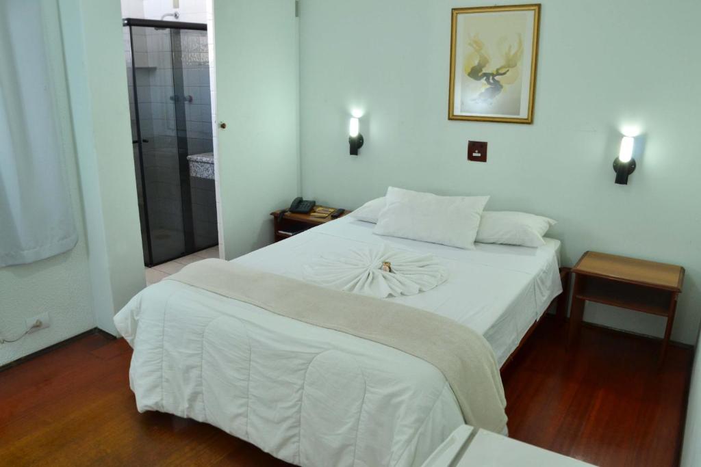 a bedroom with a large white bed and a window at Hotel Dias - By UP Hotel in Pouso Alegre