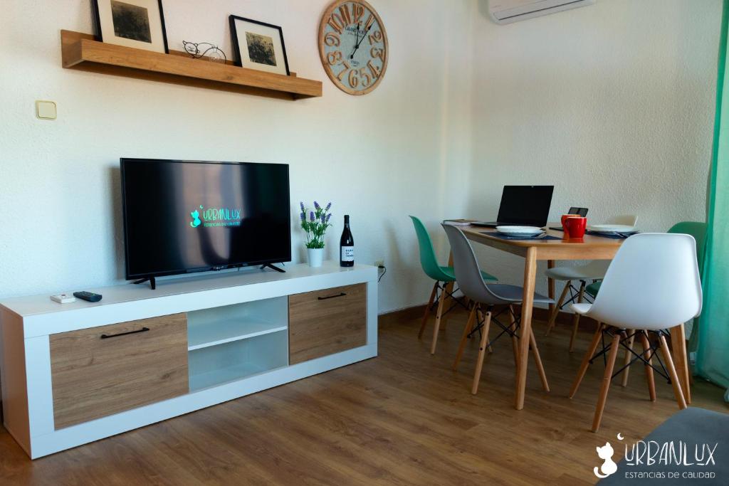 uma sala de estar com uma televisão e uma mesa com cadeiras em UrbanLux Hospital em Albacete