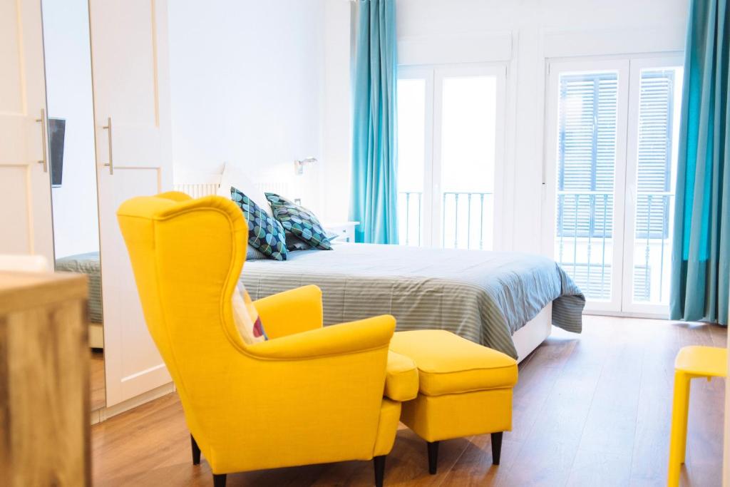 Un dormitorio con una silla amarilla y una cama en Blonski-Yellow, en Málaga