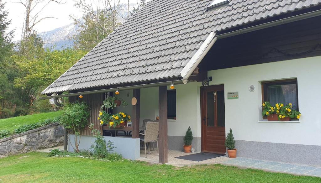 a white house with a black roof and a door at Apartment Sonce in Bohinj