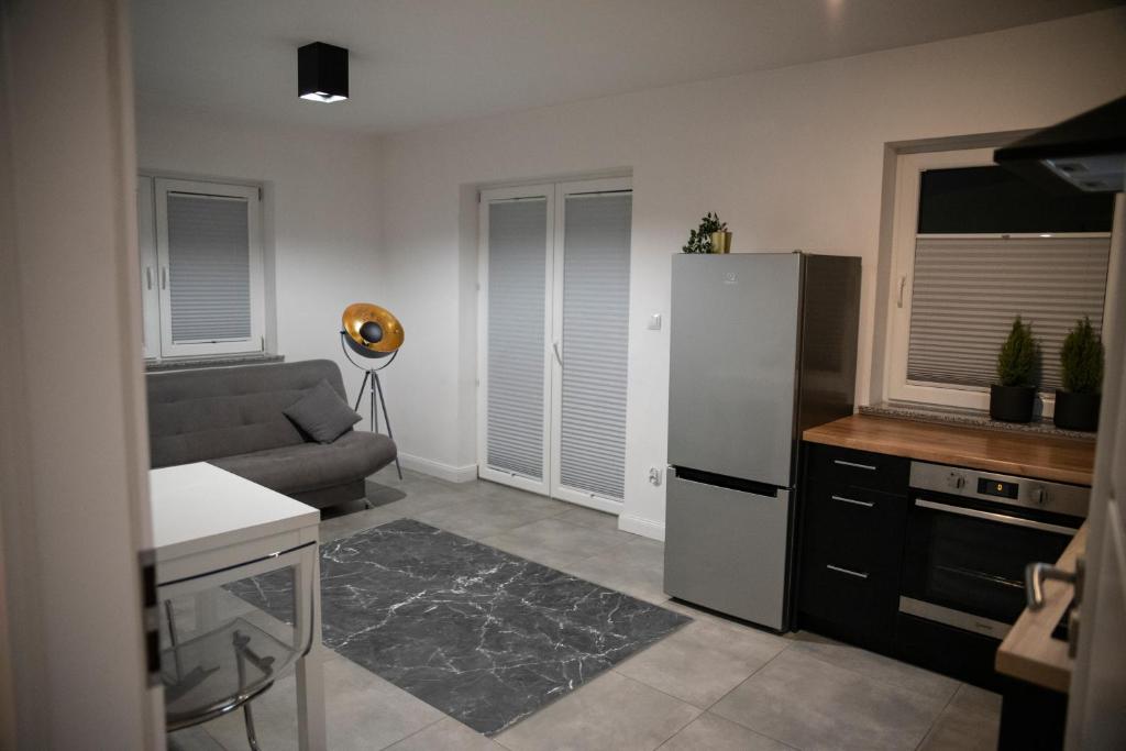 a kitchen with a refrigerator and a couch in a room at Apartament Jana Pawła in Nowy Sącz