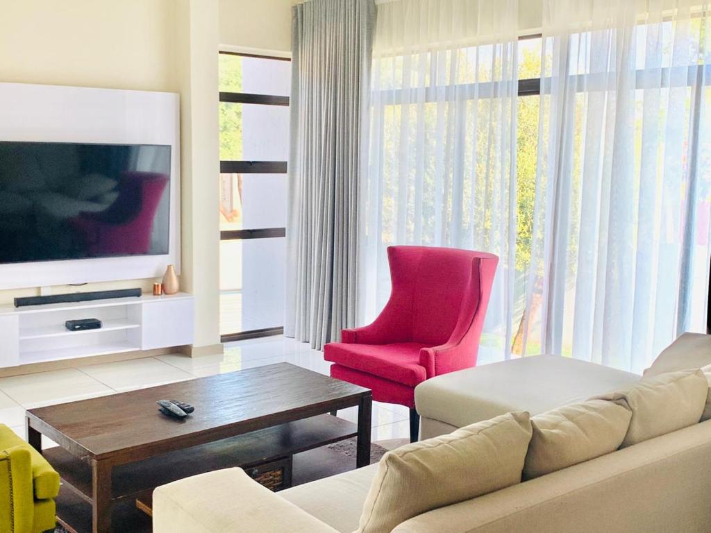 a living room with a couch and a red chair at 774Ways Holiday Home in Hartbeespoort