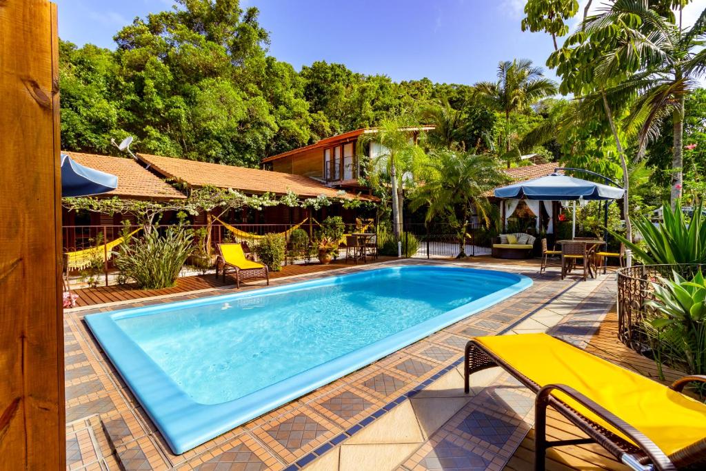 a swimming pool with chairs and a house at Estalagem Don Pablo in Bombinhas