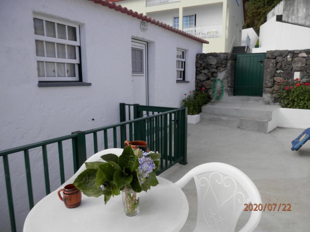 une table et des chaises blanches avec un vase de fleurs. dans l'établissement Adega Jaquet, à Biscoitos