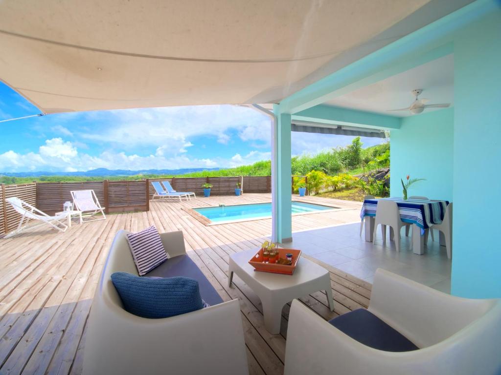 une terrasse avec un mobilier blanc et une piscine dans l'établissement SeaCove & SeaSide Villas, classées 4 étoiles, à Les Trois-Îlets
