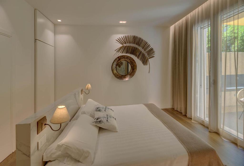 a white bedroom with a large bed and a mirror at Le Palmette Suites in Cagliari