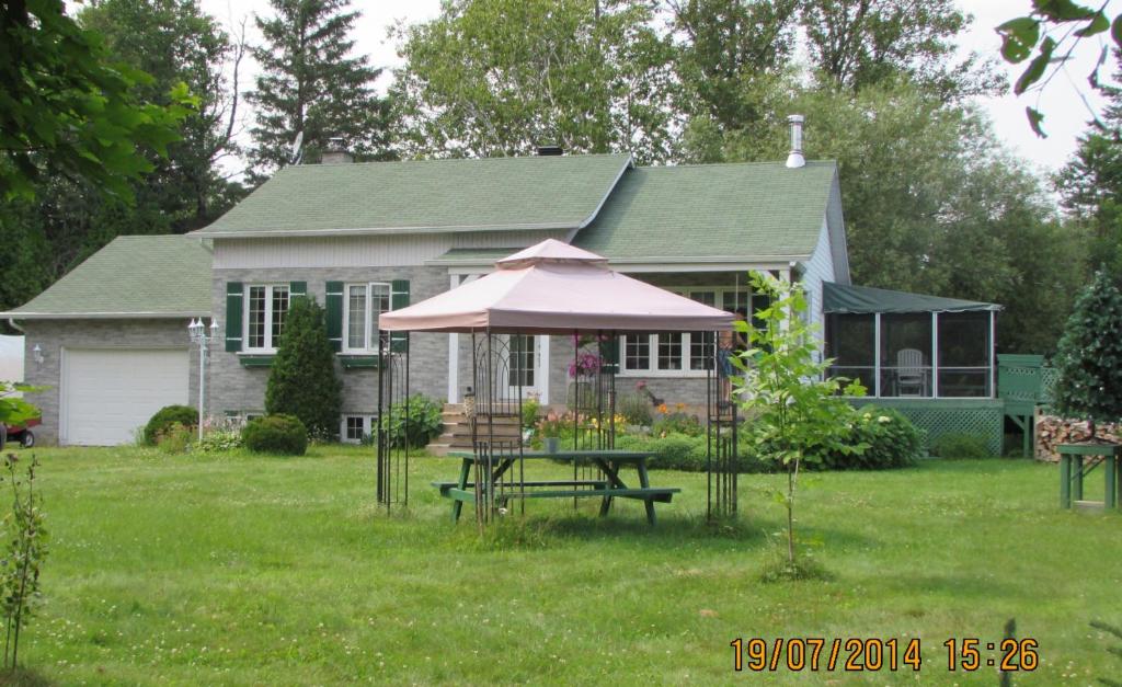 une maison avec une table de pique-nique et un parasol dans l'établissement Gîte Parc Mauricie B&B, à Saint-Mathieu-du-Parc