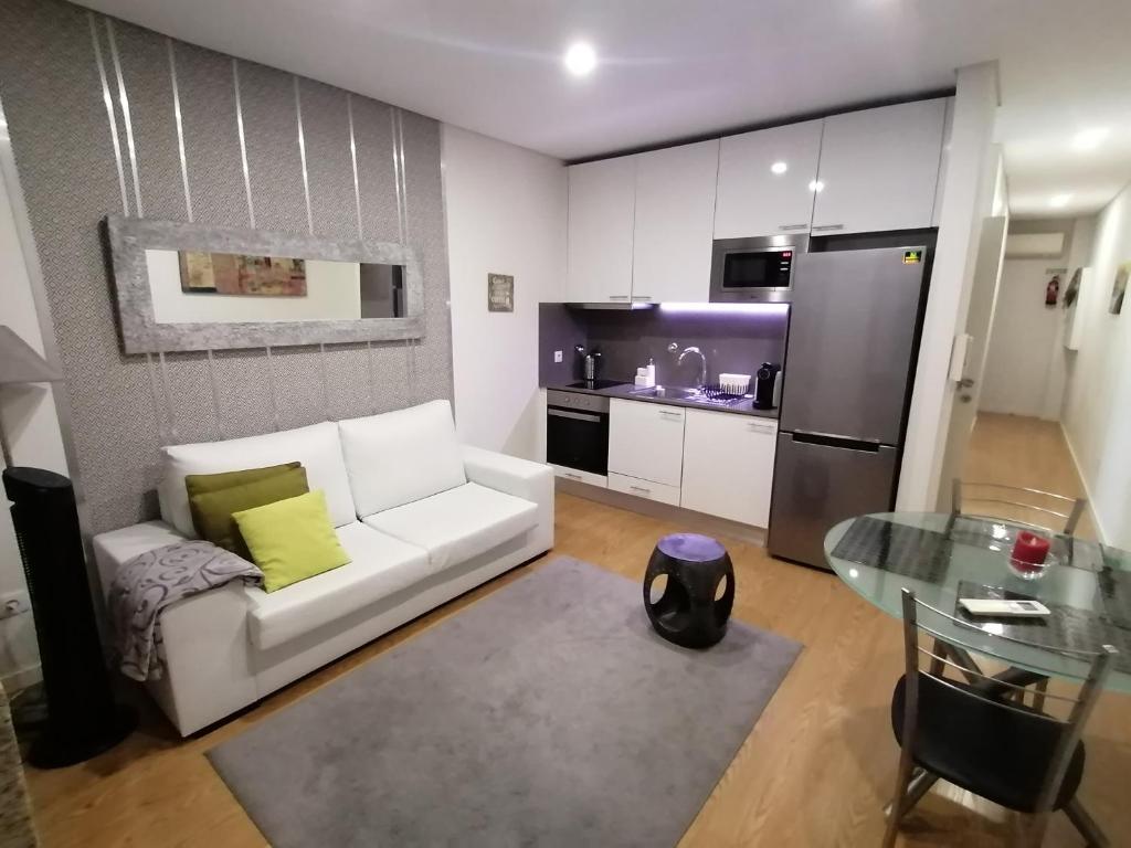 a living room with a white couch and a kitchen at Cativo Flat in Porto