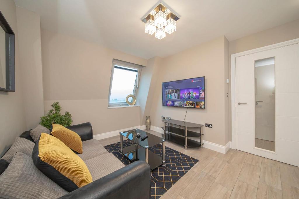 a living room with a couch and a tv at MORDEN 1 BEDROOM 5 mins away from brighton seafront in Brighton & Hove