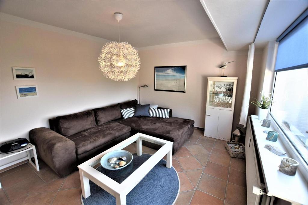 a living room with a brown couch and a chandelier at Muschelkiste-H in Hohwacht