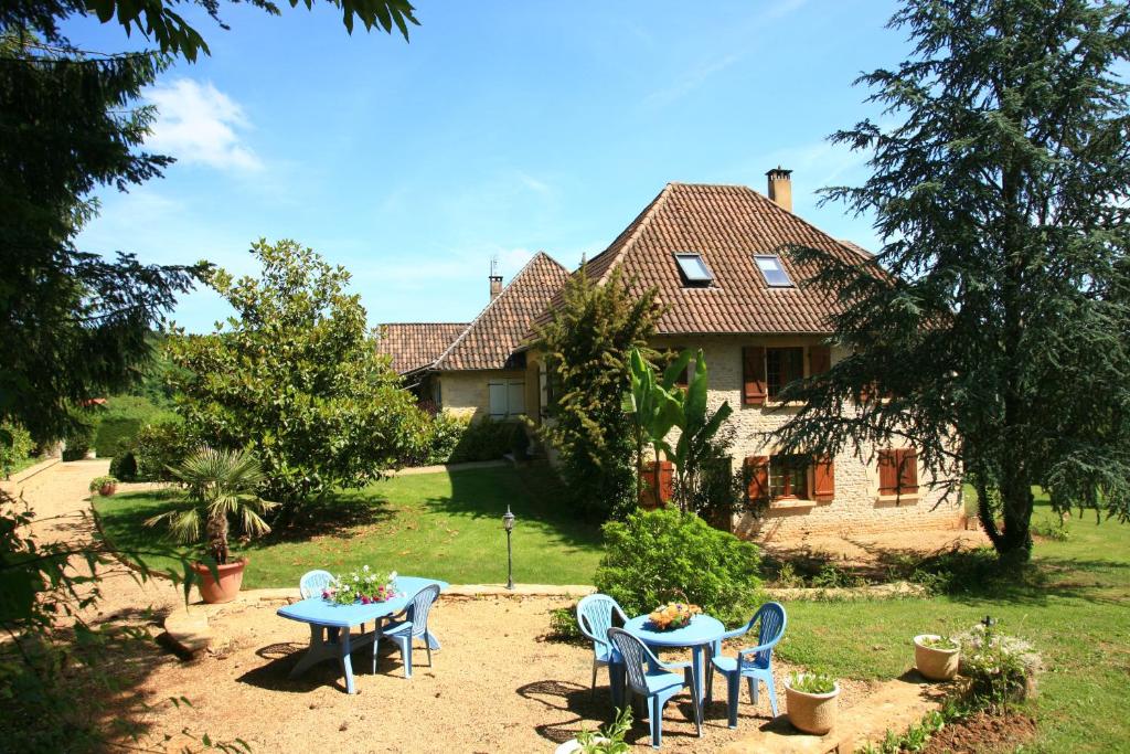 a house with tables and chairs in front of it at Chambres d'Hôtes Larnaudie in Saint-Amand-de-Coly