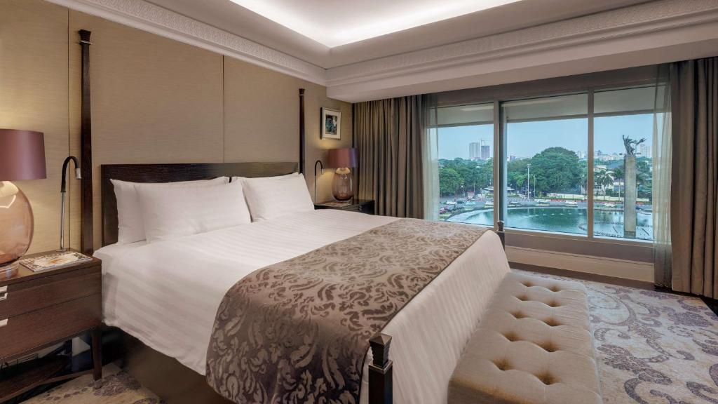 ein Schlafzimmer mit einem großen Bett und einem großen Fenster in der Unterkunft Hotel Indonesia Kempinski Jakarta in Jakarta