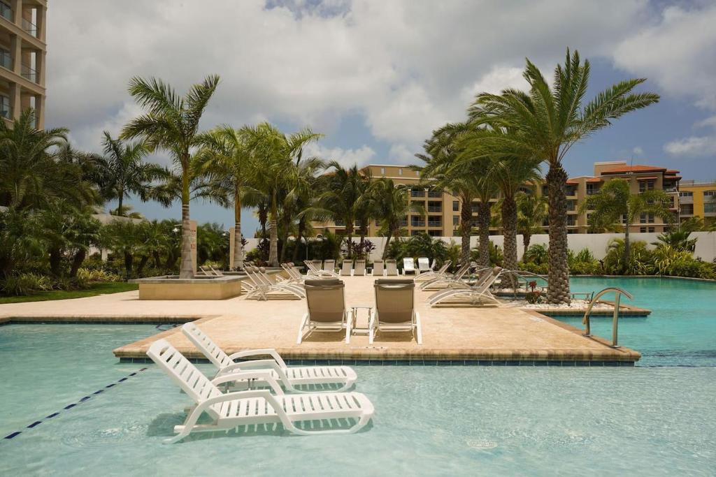 une piscine avec chaises longues et palmiers dans l'établissement Elegant apartment in eagle beach levent, à Palm-Eagle Beach