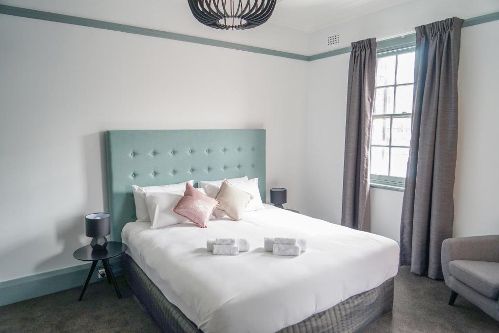 a bedroom with a large white bed with pink pillows at Oasis on Beamish Hotel in Sydney