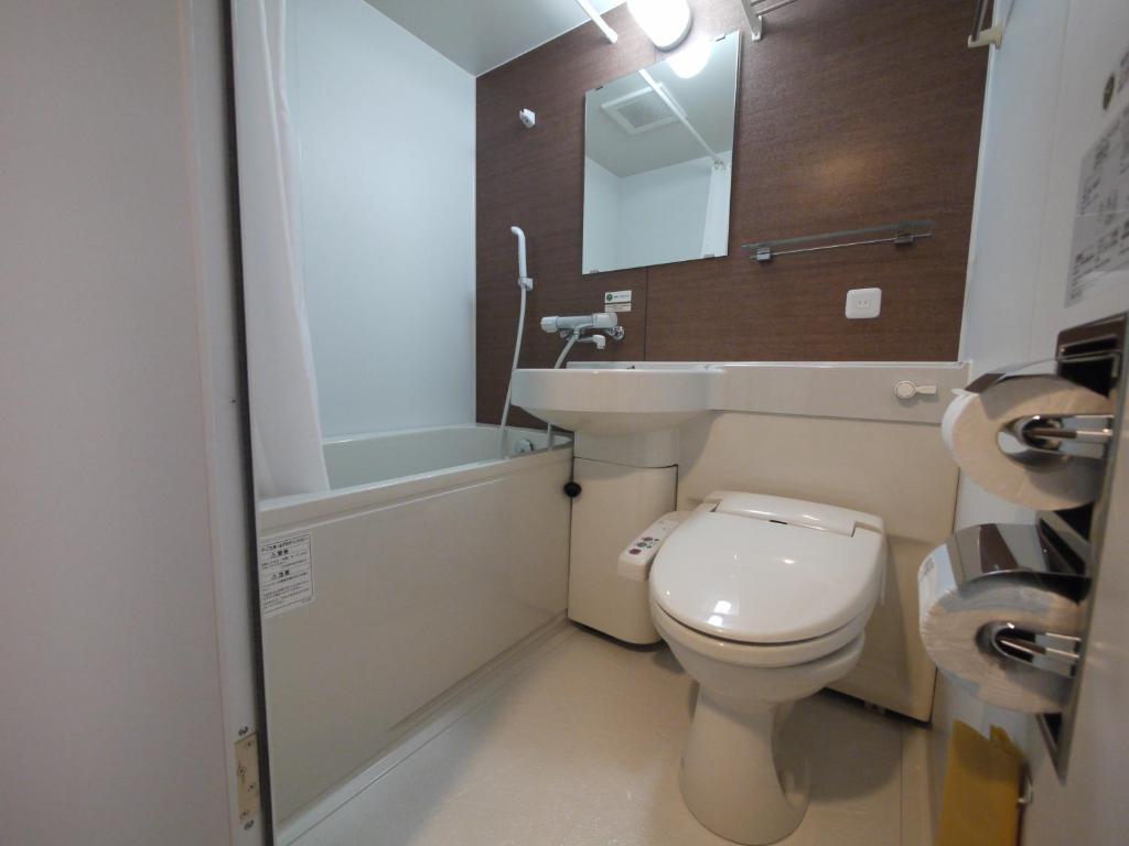 
a white toilet sitting next to a white sink at Hotel Route-Inn Kitamatsudo Ekimae in Matsudo
