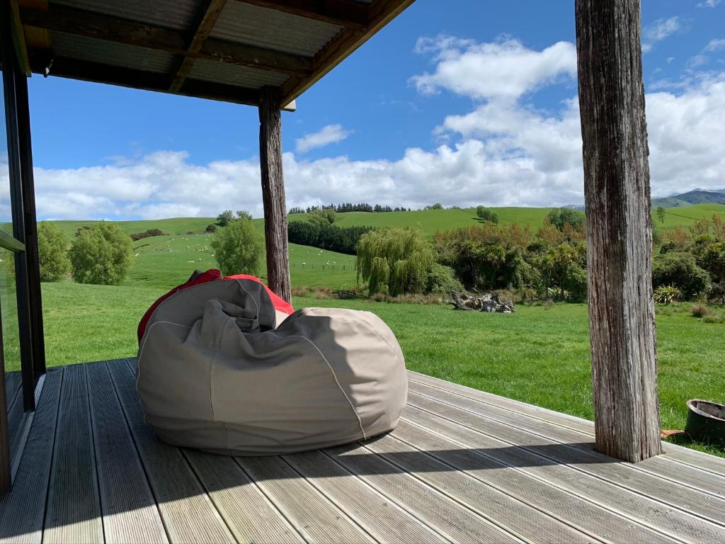 a bag sitting on a wooden porch with a view of a field at Fallow Hut in Masterton