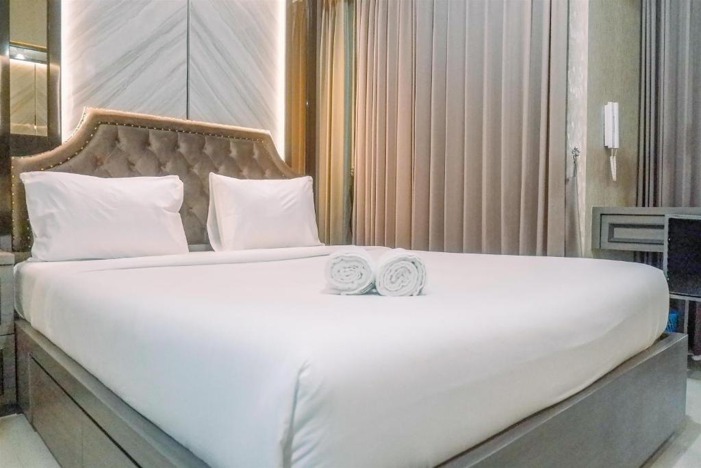 a large white bed with two towels on it at Classic Studio Room Apartment at Taman Melati Surabaya By Travelio in Surabaya