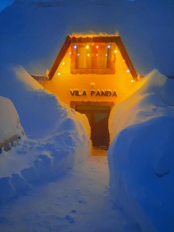 dom pokryty śniegiem z oświetleniem w obiekcie Vila Panda w mieście Rânca
