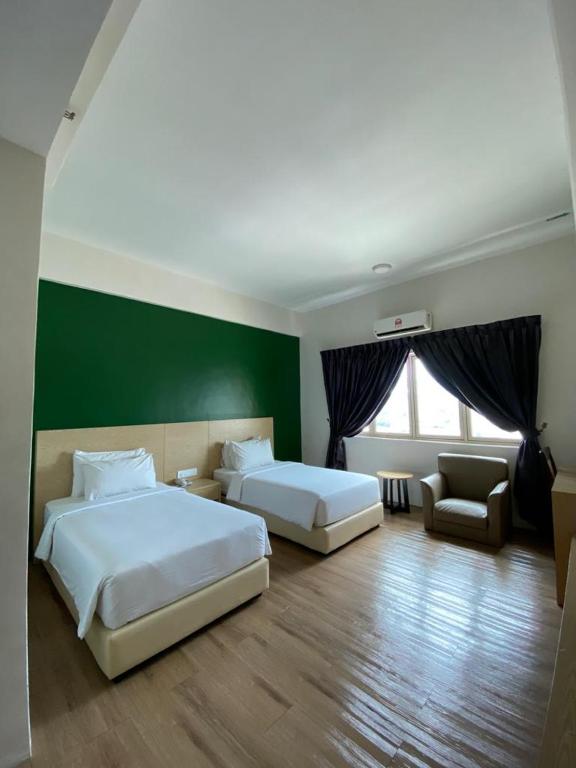 バトゥパハにあるSummit Signature Hotel Batu Pahatの緑の壁のベッドルーム1室(ベッド2台付)