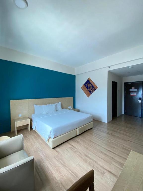 バトゥパハにあるSummit Signature Hotel Batu Pahatの青い壁のベッドルーム1室(大きな白いベッド1台付)