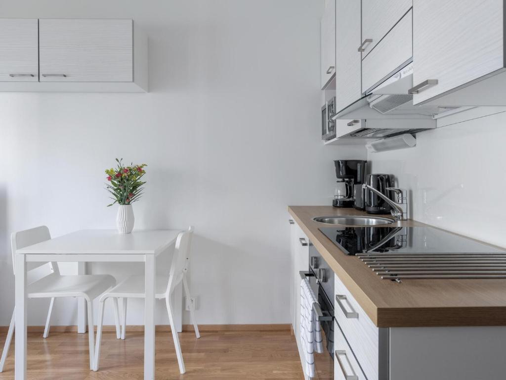 a kitchen with a table and a white table and chairs at Kotimaailma Apartments Joensuu - Koulukatu 21 in Joensuu