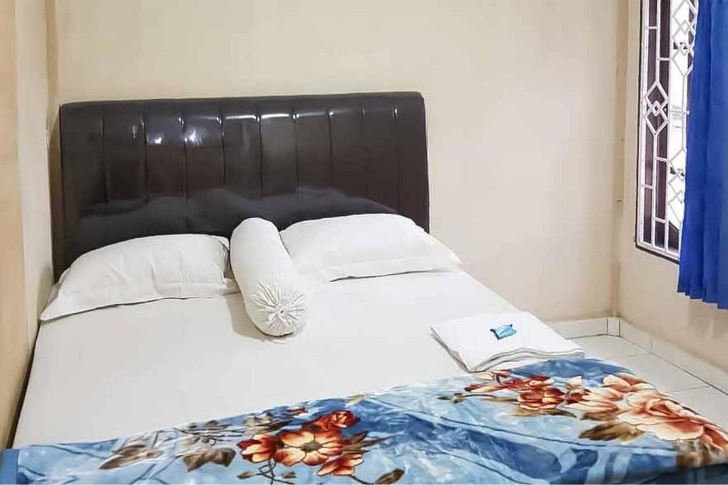 Bett mit schwarzem Kopfteil und weißen Kissen in der Unterkunft Airangga Home Stay Syariah Berastagi RedPartner in Berastagi