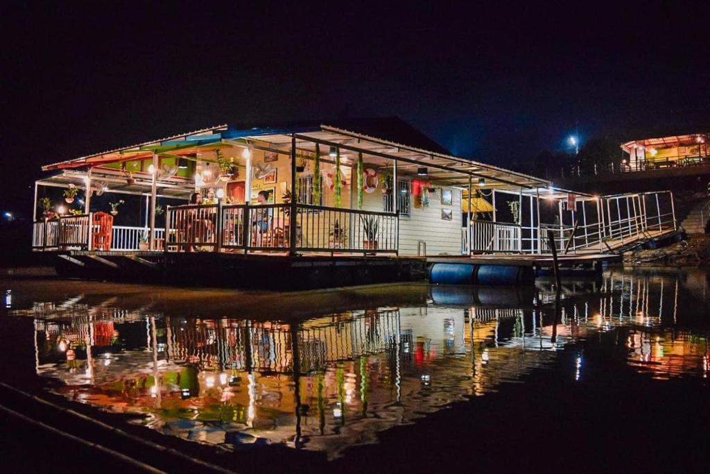 a building with lights on the water at night at Ruanmai Style Resort 2 in Ban Nong Nam Khan