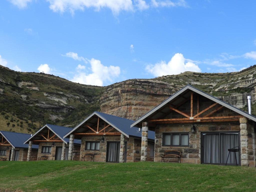 una fila di case di tronchi di fronte a una montagna di Oranje Guest Farm a Fouriesburg