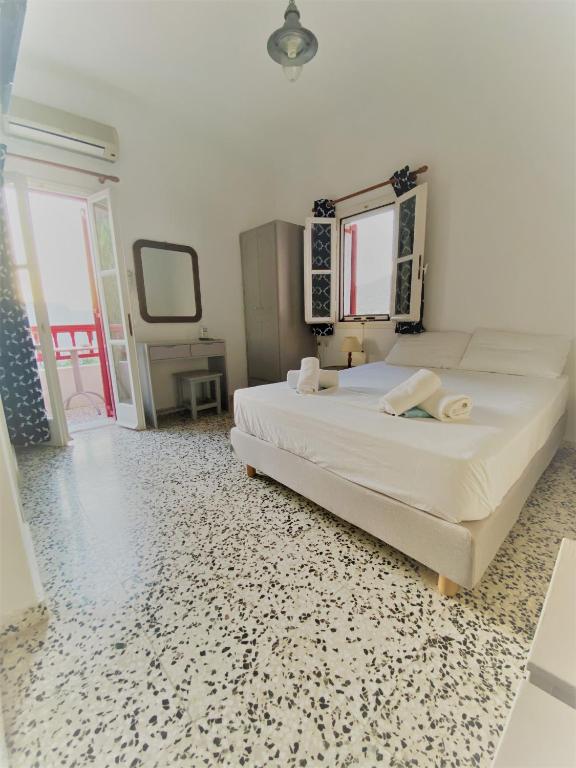 a bedroom with a large white bed with a mirror at Anna Studios in Katapola