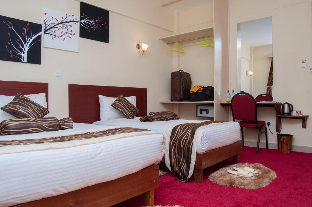 a bedroom with two beds and a red carpet at Merril Hotel in Eldoret