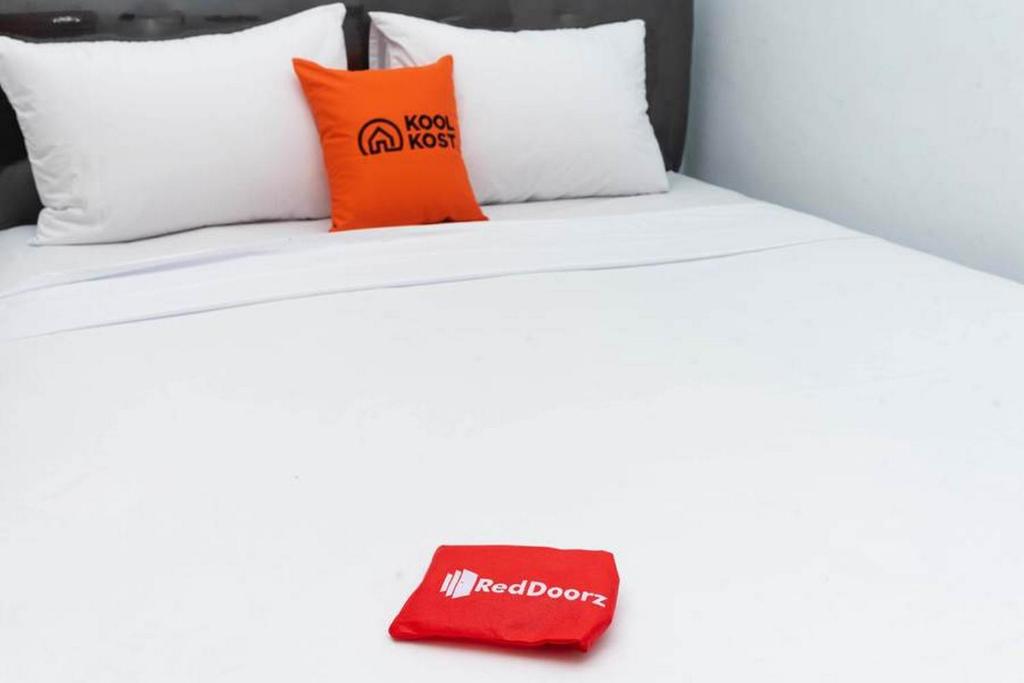 Una cama con dos almohadas y un libro rojo. en RedDoorz Brand MAN12045 RedDoorz near Megamall Manado, en Manado