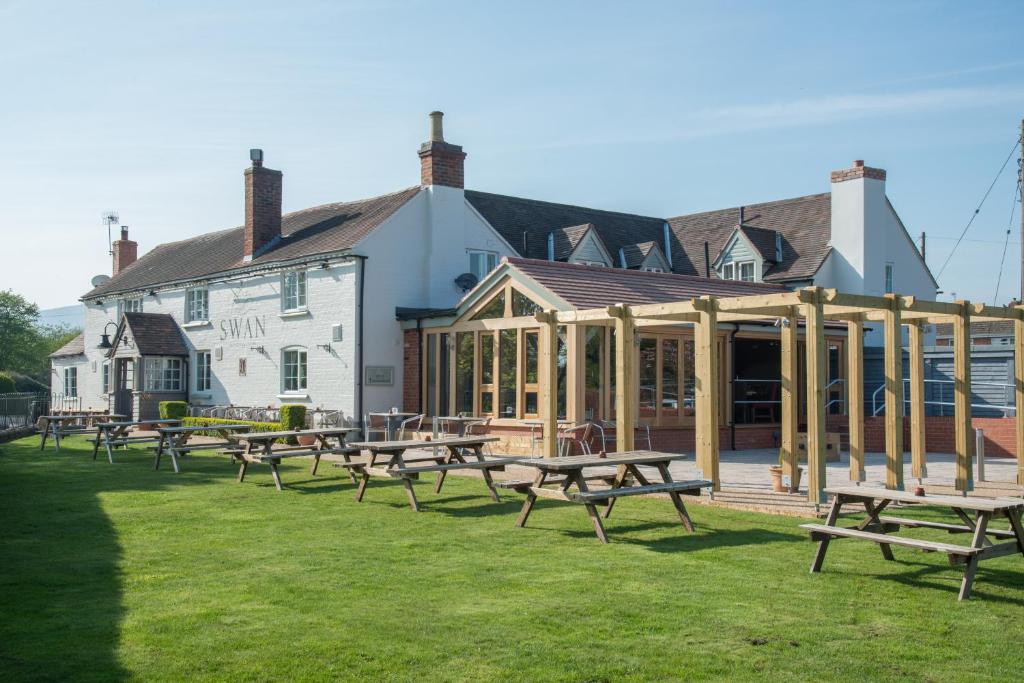 un groupe de tables de pique-nique devant un bâtiment dans l'établissement The Swan Inn, à Hanley Castle