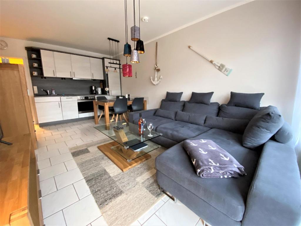 un soggiorno con divano blu e una cucina di Appartmenthaus Witthöhn, Whg. 2 a Cuxhaven