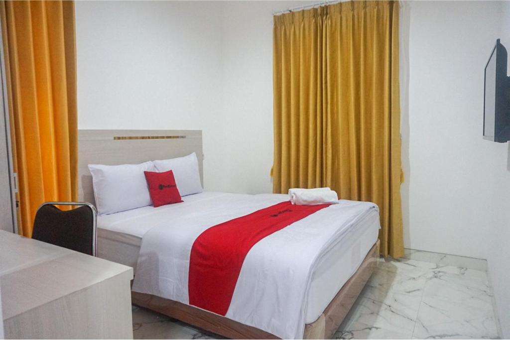 een slaapkamer met een bed met een rode en witte deken bij RedDoorz near Araya Family Club House in Malang