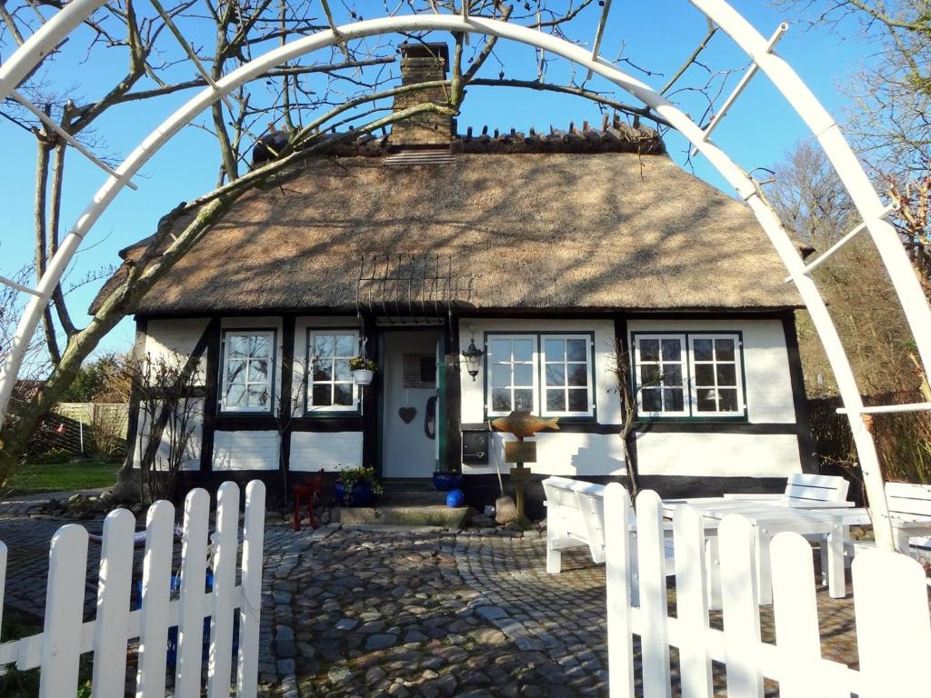 ein Cottage mit einem weißen Gartenzaun davor in der Unterkunft Ferienhaus Rikate in Kappeln