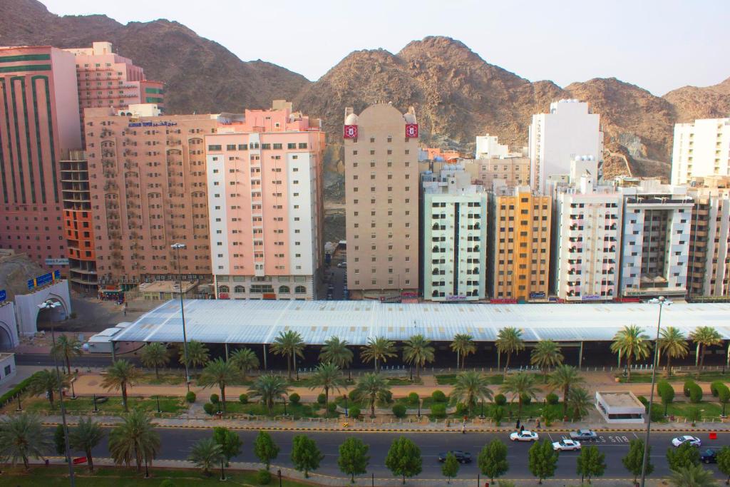 a city with buildings and palm trees and mountains at Al Jaad Mahbas Hotel in Makkah