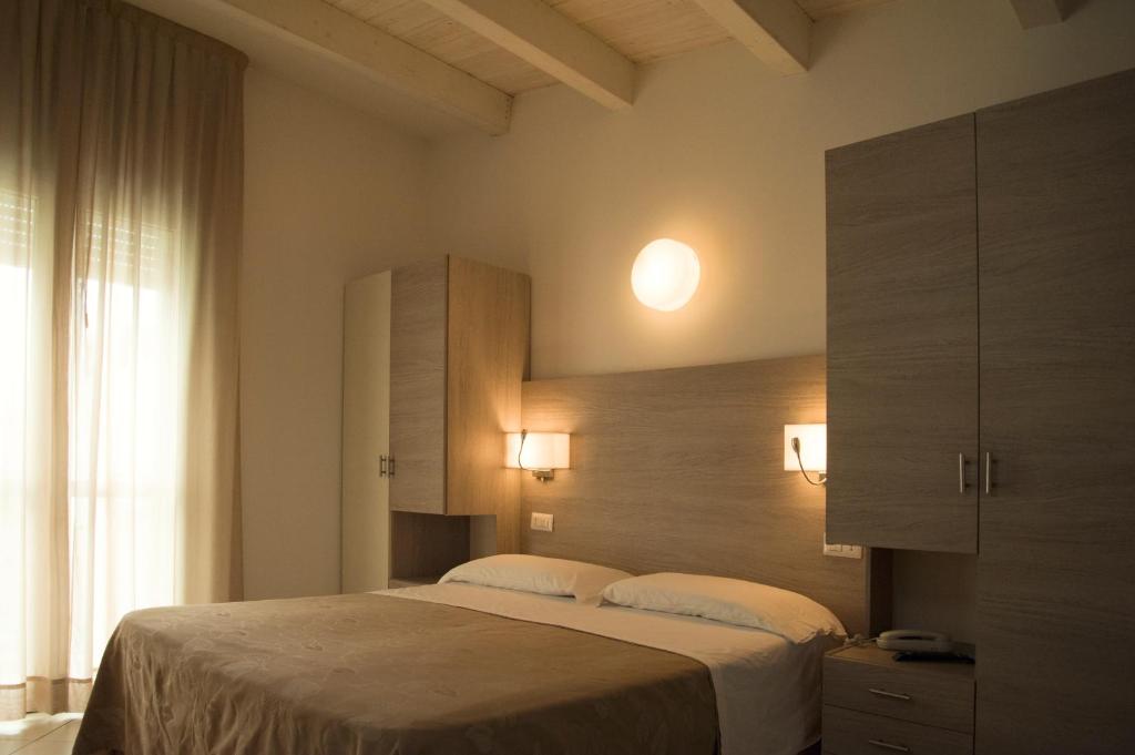 a bedroom with a large bed and a large window at Hotel Villa Enea in Cattolica