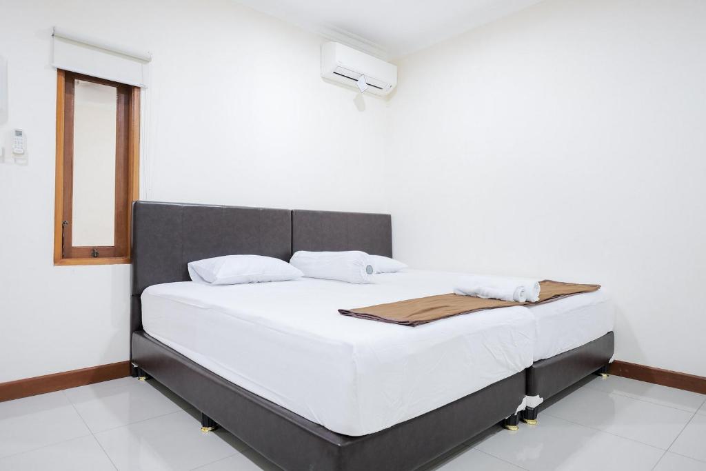 Schlafzimmer mit einem Bett mit weißer Bettwäsche und einem Fenster in der Unterkunft wisma delapan Mitra RedDoorz in Jakarta