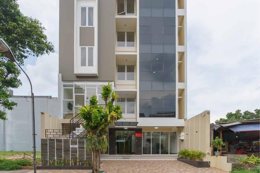 a tall white building with a palm tree in front of it at RedDoorz Plus near Eka Hospital BSD 5 in Tangerang