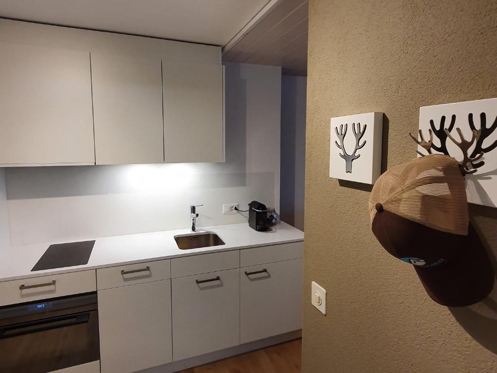 a kitchen with white cabinets and a hat on the wall at Zentrum Lai 176 Hm Whg 103 Steibogg in Lenzerheide