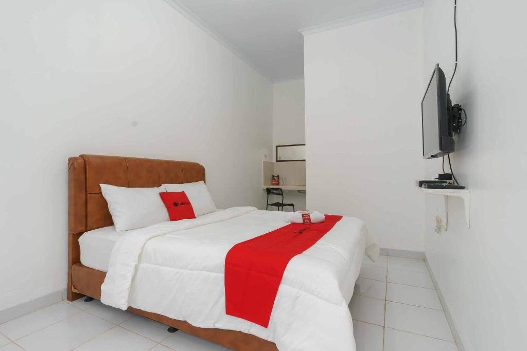 um quarto com uma cama com um cobertor vermelho e branco em RedDoorz Syariah near Exit Toll Jatiwarna 2 em Pondokmelati