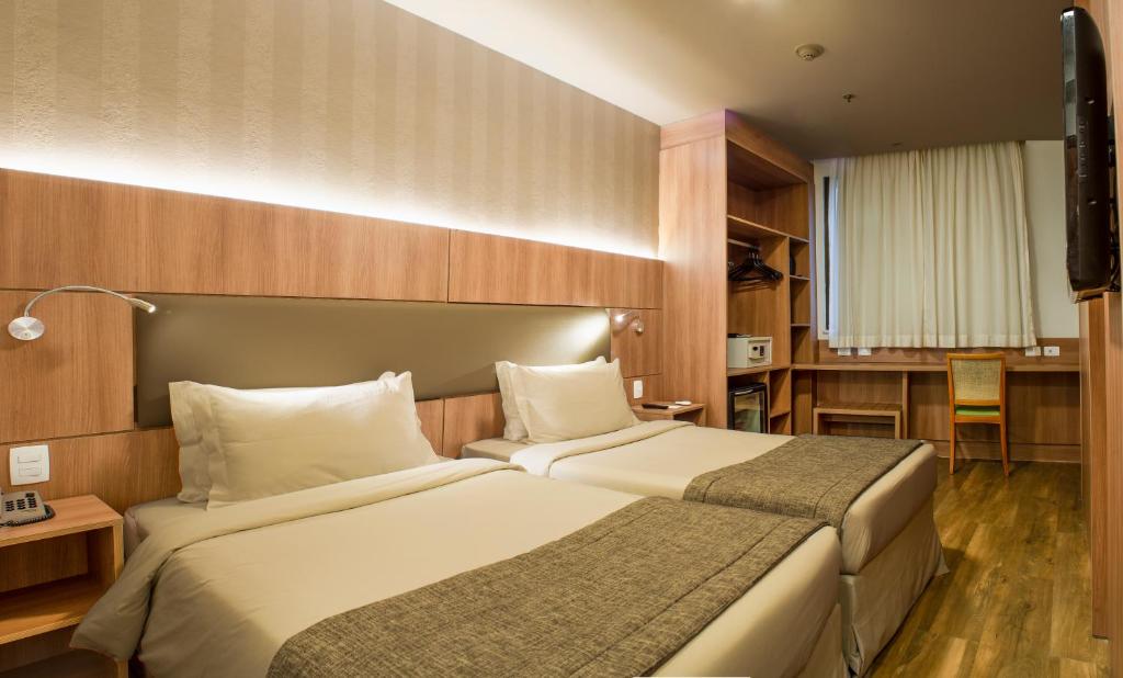 a hotel room with two beds and a desk at Hotel Astoria Copacabana in Rio de Janeiro