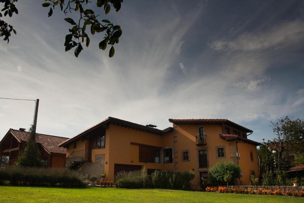Apartamentos Rurales La Casa Vieja De Silió في Silió: منزل في ساحة ذات سماء غائمة