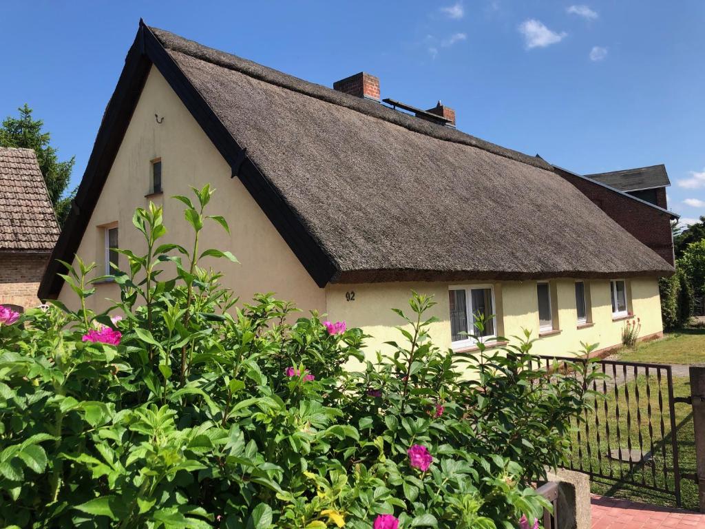 ein gelbes Haus mit einem Strohdach und rosa Blumen in der Unterkunft Dat Reethus Grambin in Grambin