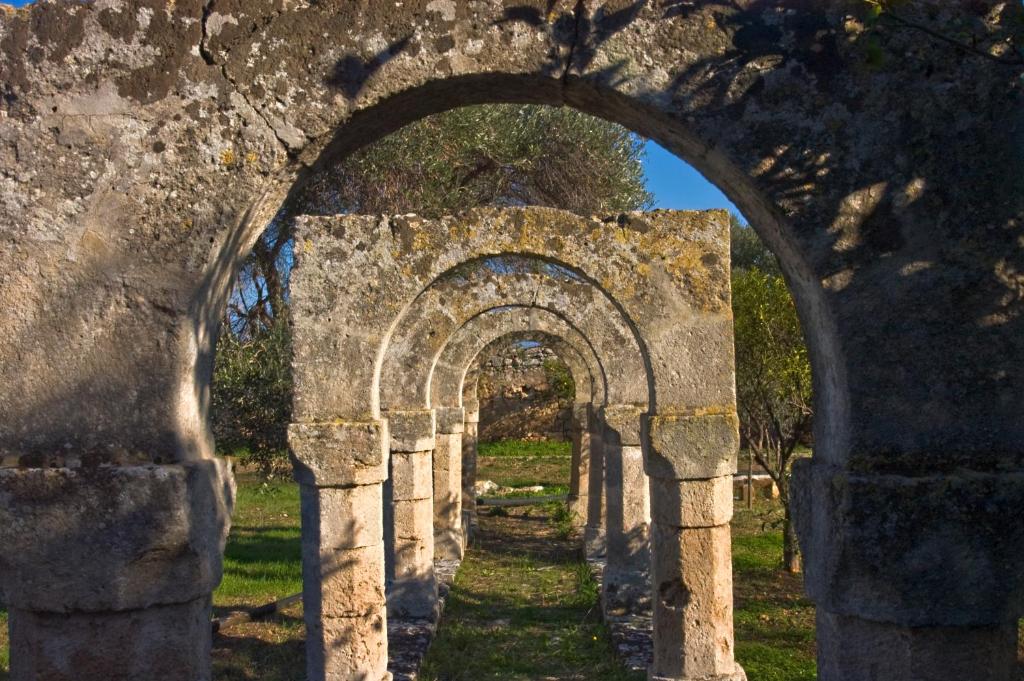 an archway in a field with grass and trees at Masseria Spina Resort in Monopoli